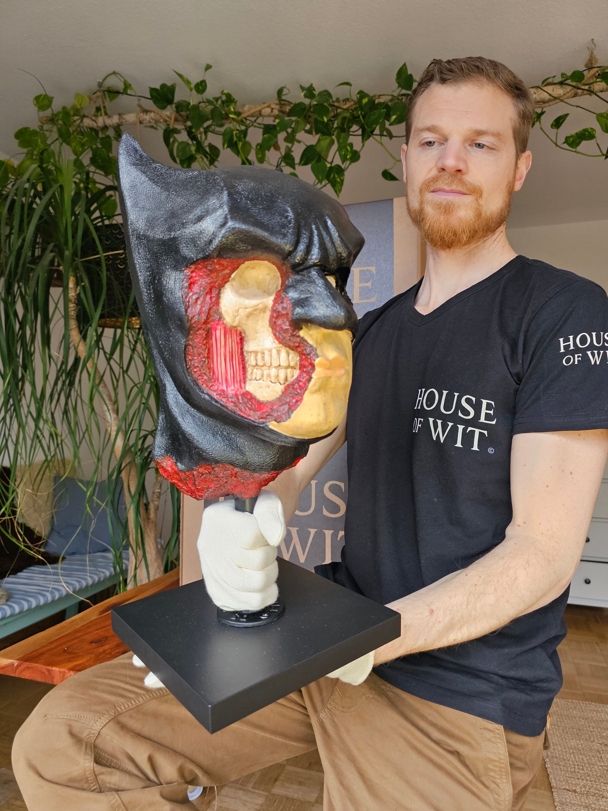 “House of Wit Batman anatomical bust, three-quarter view with exposed skull and red muscle on right side of face.”