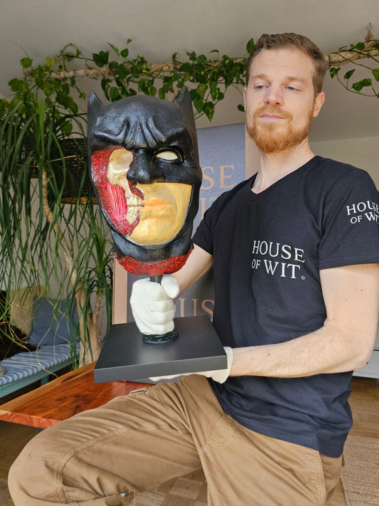 “House of Wit Batman anatomical bust on black stand, front view showing stern expression and black cowl.”