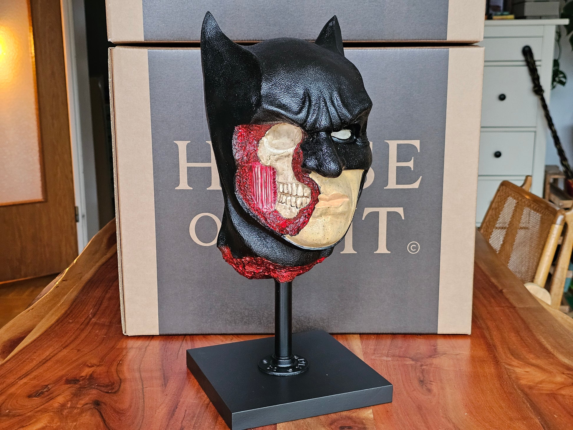 “Close-up of Batman bust face, black cowl and pale skin with intense, stylized comic-book expression.”