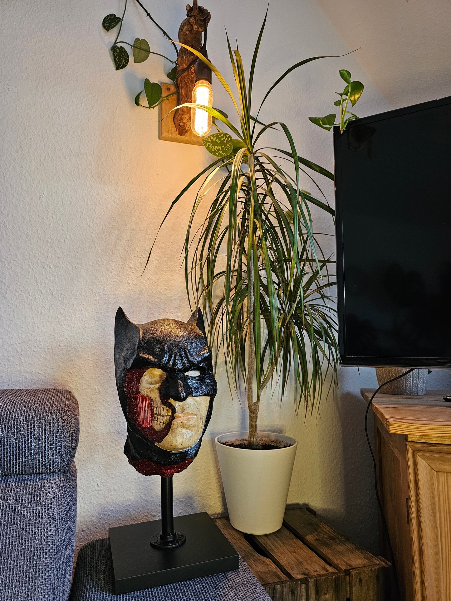 “Batman anatomical bust displayed on a desk in a living space, showing how the sculpture fits into home decor.”

