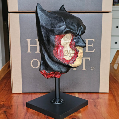 “Side profile of Batman anatomical bust showing detailed skull, teeth, and red facial muscles under black cowl.”

